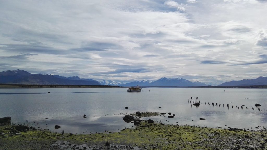 Hajó úszik a sima víztükrön Puerto Natalesnél